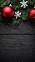 Christmas decorations with red baubles, snowflakes, and pine branches on a dark wooden vertical background. Flat lay composition with copy space for holiday designs photo