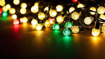 Glowing yellow, green, and red string lights spread across a dark surface. Festive and decorative lighting for holiday and seasonal designs. Copy space photo