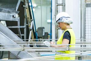 Female industrial engineer wearing a white helmet while standing in a heavy industrial factory photo