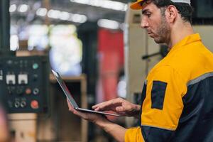 Caucasian engineer using a laptop in a factory. man working in plastics factory. photo
