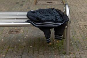 black jacket is hanging on a metal bench. The jacket is hanging upside down and is not being used photo