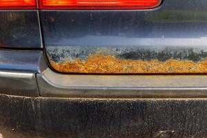 A close-up view of a car's rear bumper showing significant rust damage photo