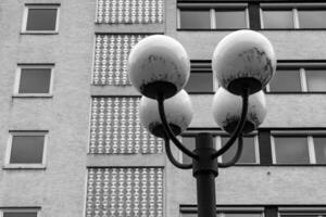 A street lamp stands in front of a building with windows and patterned tiles photo