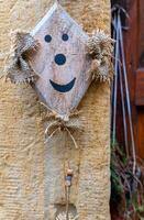 A wooden sign with a smiling face is hanging on a stone wall in a quaint village photo