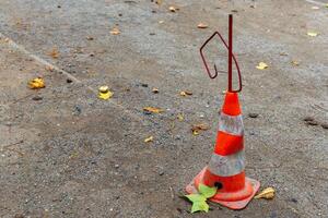 A traffic cone sits on a gravel road with some fallen leaves around it photo