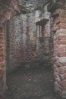 A small, windowless room in a stone ruin with a barred window overlooking the courtyard photo