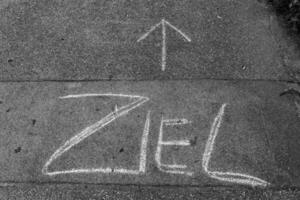 The word Ziel, meaning goal in German, is written on the sidewalk with an arrow pointing upward photo