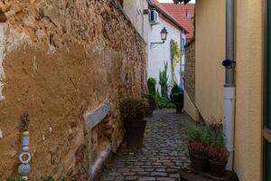 A narrow, cobblestone alleyway winds between two buildings in an old town photo