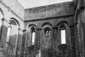 A view of the interior of a ruined building in Ireland, with windows and arches framing a view of the sky photo