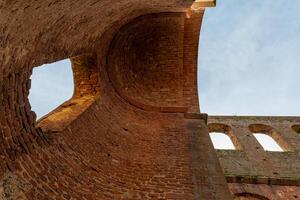 A view of the arched ceiling of an old stone building, looking up to the blue sky photo
