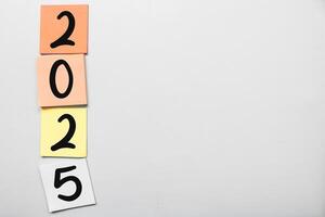 New year's resolutions 2025 on the sticky note isolated gray background. New year concept with typographic 2025. Motivational words for the new year 2025 photo
