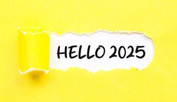 Hello 2025 word on white background and torn yellow paper. New year concept with typographic Hello 2025 on paper. Motivational words for the new year 2025 photo