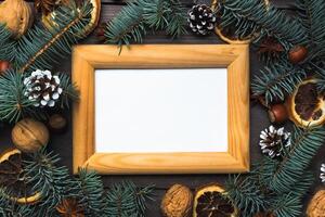 Frame of Christmas tree cones oranges nuts on dark wooden background. Copy space. Flat lay. Wooden frame and space for text. photo