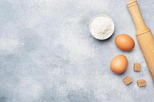 Ingredients for baking cookies, cupcakes and cake. Raw foods eggs flour sugar on a grey background with copy space. photo