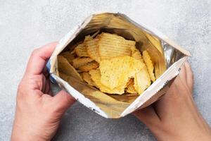 Potato chips with spicy in an open package hold hands. Close up Selective focus. photo