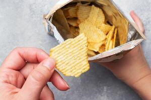 Potato chips with spicy in an open package hold hands. Close up Selective focus. photo