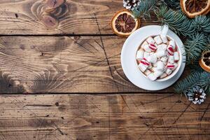 A Cup of hot chocolate with marshmallows. Christmas tree and decorations, cane caramel and oranges nuts Wooden background copy space. photo