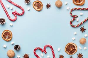 Cup of hot chocolate with marshmallow cocoa powder and caramel nuts, oranges on pastel blue background with copy space. Christmas winter concept. photo