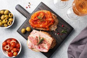 Whole grain bread sandwiches with cream cheese, bacon and canned peppers with tomato on a wooden cutting Board. Gray concrete background with Copy space. photo