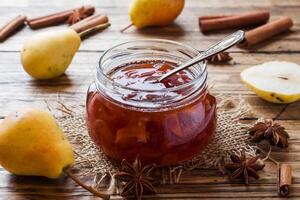 Homemade pear jam in a jar and fresh pears on a wooden background. photo
