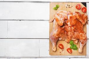 Raw chicken tobacco on a wooden Board with spices and vegetables Copy space photo