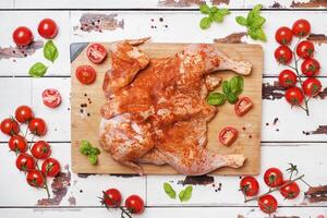 Raw chicken tobacco on a wooden Board with spices and vegetables. photo