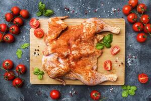 Raw chicken tobacco on a wooden Board with spices and vegetables. photo