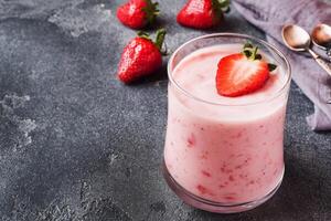 Homemade yogurt with fresh strawberries in glasses on a dark concrete background. Selective focus. Copy space. photo