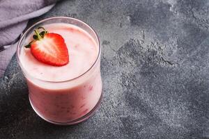 Homemade yogurt with fresh strawberries in glasses on a dark concrete background. Selective focus. Copy space. photo