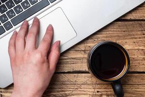 Working wooden table at home or in the office. Computer laptop coffee cactus. Flat lay conceptions Woman working at computer hands. photo