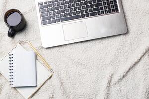Notebook Computer and coffee lying on a white wool blanket. Concept of working and learning at home. Copy space. photo