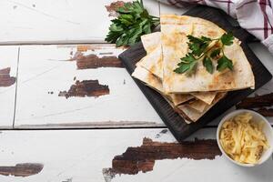 Pieces of quesadilla with mushrooms sour cream and cheese on a wooden stand with parsley leaves. Wooden background copy space. photo