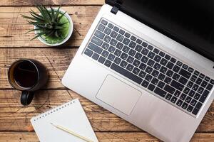 Working wooden table at home or in the office. Computer laptop coffee cactus. Flat lay conceptions Copy space. photo