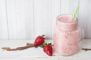 Homemade yogurt with fresh strawberries in a glass jar on a white wooden background. Selective focus. Copy space. photo