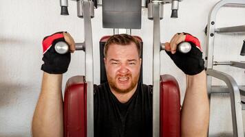 Caucasian man straining while using weight machine in the gym, focusing on fitness and physical challenge photo