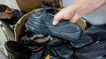 Hand selecting sandals from a pile highlighting quality control and manufacturing processes photo