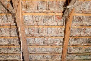 Close up of a deteriorating wooden attic ceiling with exposed beams, related to home renovation and structural integrity issues photo