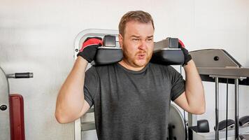 A Caucasian man struggles while lifting weights in a gym, illustrating the challenges of maintaining fitness resolutions photo