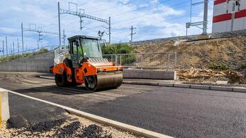 A road roller compacts fresh asphalt on a construction site, highlighting infrastructure development and urban improvement projects photo