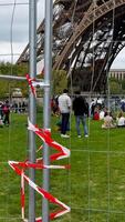 Visitors gather around a fenced off area near the Eiffel Tower, highlighting tourism and security measures in Paris photo