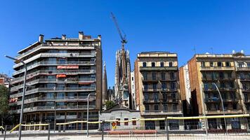 Modern and historical architecture meet as the Sagrada Familia towers behind Barcelona apartments under construction, symbolizing urban development and cultural heritage photo