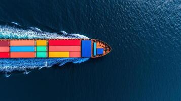 Overhead shot of a cargo vessel loaded with colorful shipping containers crossing deep blue waters the ships wake forming symmetrical patterns behind it photo