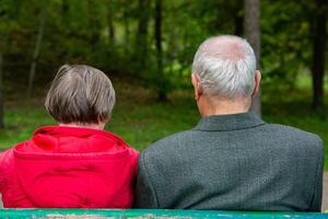 Back view of a senior couple sitting on a bench in the park. Elderly couple. photo