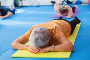 Elderly woman doing pilates exercises on a mat at home photo