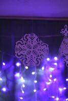Traditional Christmas and New Year decorations. Garland lights and paper snowflakes, in a home interior. photo
