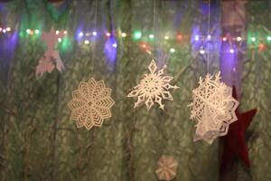 Traditional Christmas and New Year decorations. Garland lights and paper snowflakes, in a home interior. photo