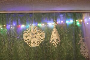 Traditional Christmas and New Year decorations. Garland lights and paper snowflakes, in a home interior. photo