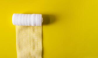 White medical bandage on yellow background close up photo