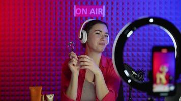 Female blogger influencer is showing eyelash curler while recording blog. Vlogger broadcasts how to use of eyelash curler video