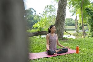 Young Woman Practicing Yoga Outdoors in a Serene Garden Setting, Embracing Nature and Relaxation photo
